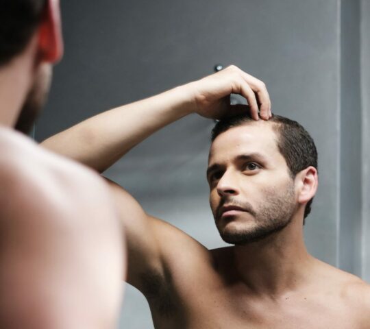 Homme s'apercevant dans le miroir que ses cheveux commencent à tomber